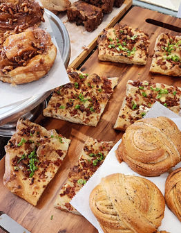 Various pastries, breads, and baked goods, Runcible Spoon Bakery display on wooden board.