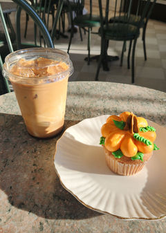 Iced coffee and flower cupcake on plate. Runcible Spoon Bakery treats.
