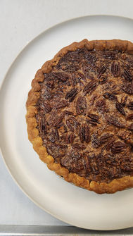 Pecan pie on a white plate, close-up shot of the delicious dessert.